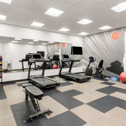Fitness room with cardio equipment, a weight bench and free weights.