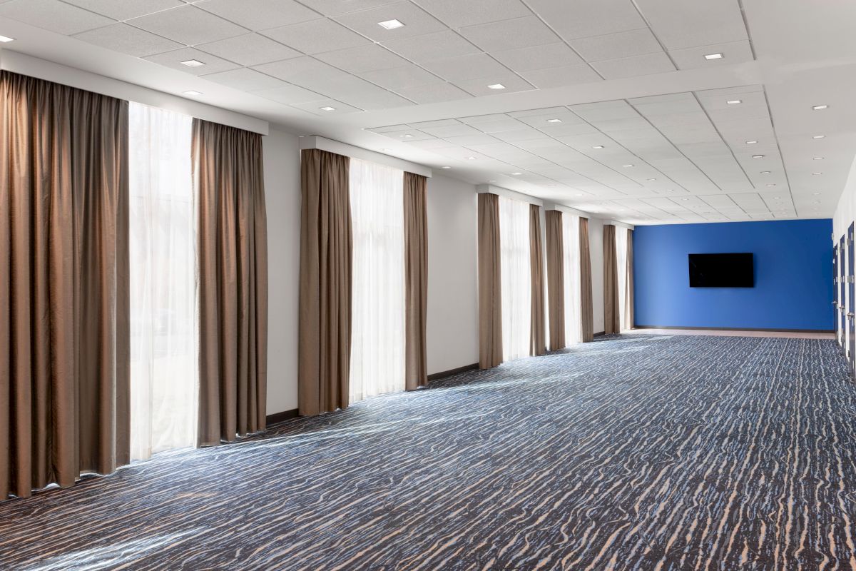 Open conference room with windows and a wall-mounted screen.