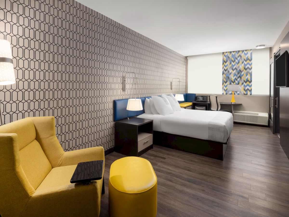 King guest room with a yellow lounge chair, work desk and television.