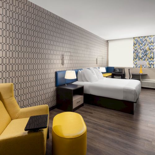 King guest room with a yellow lounge chair, work desk and television.