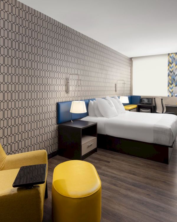 King guest room with a yellow lounge chair, work desk and television.