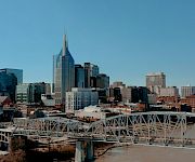 Downtown skyline with skyscrapers and a white steel bridge over a river under a clear blue sky.