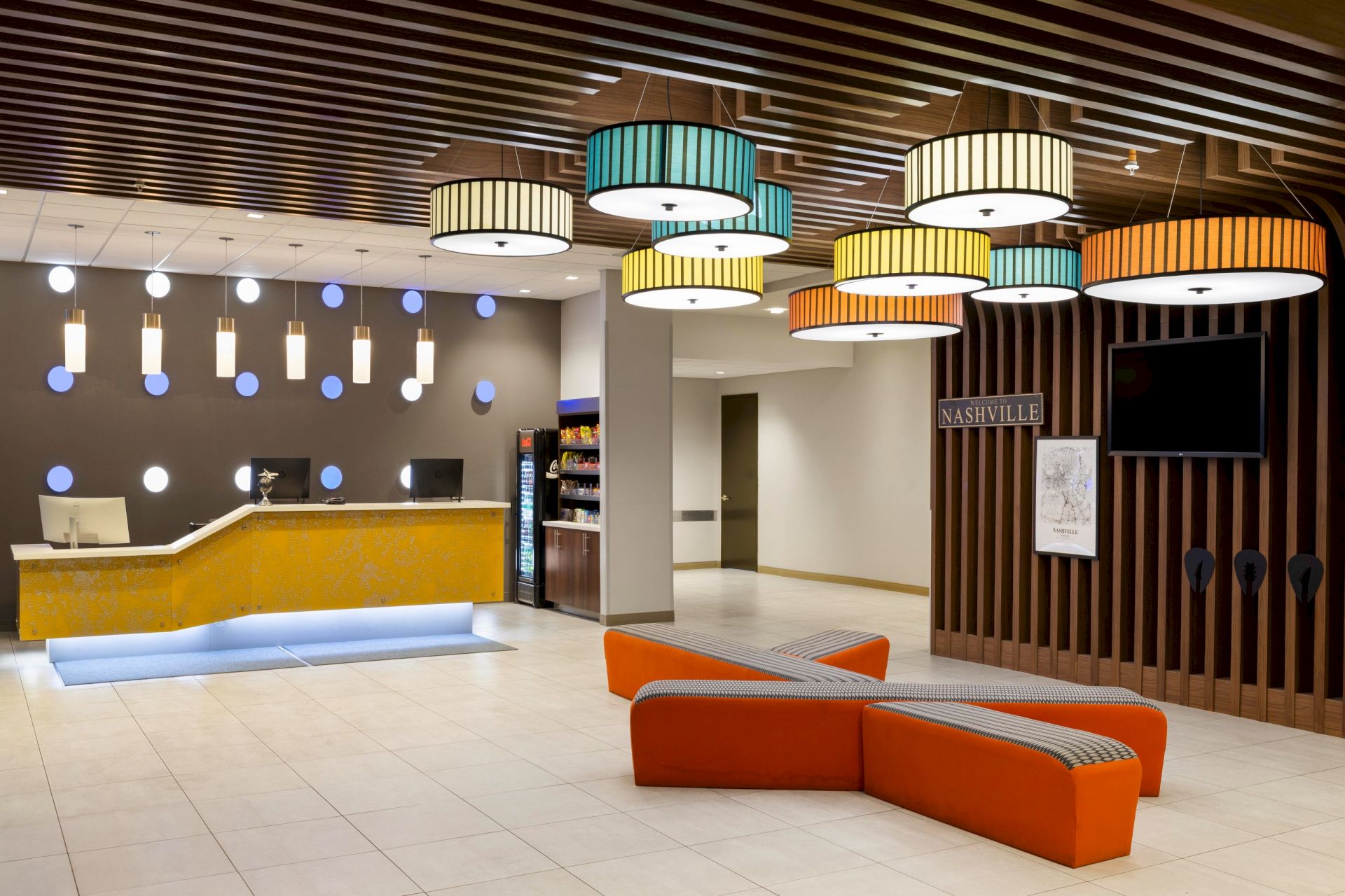 Hotel lobby with colorful pendant lights and orange seating.