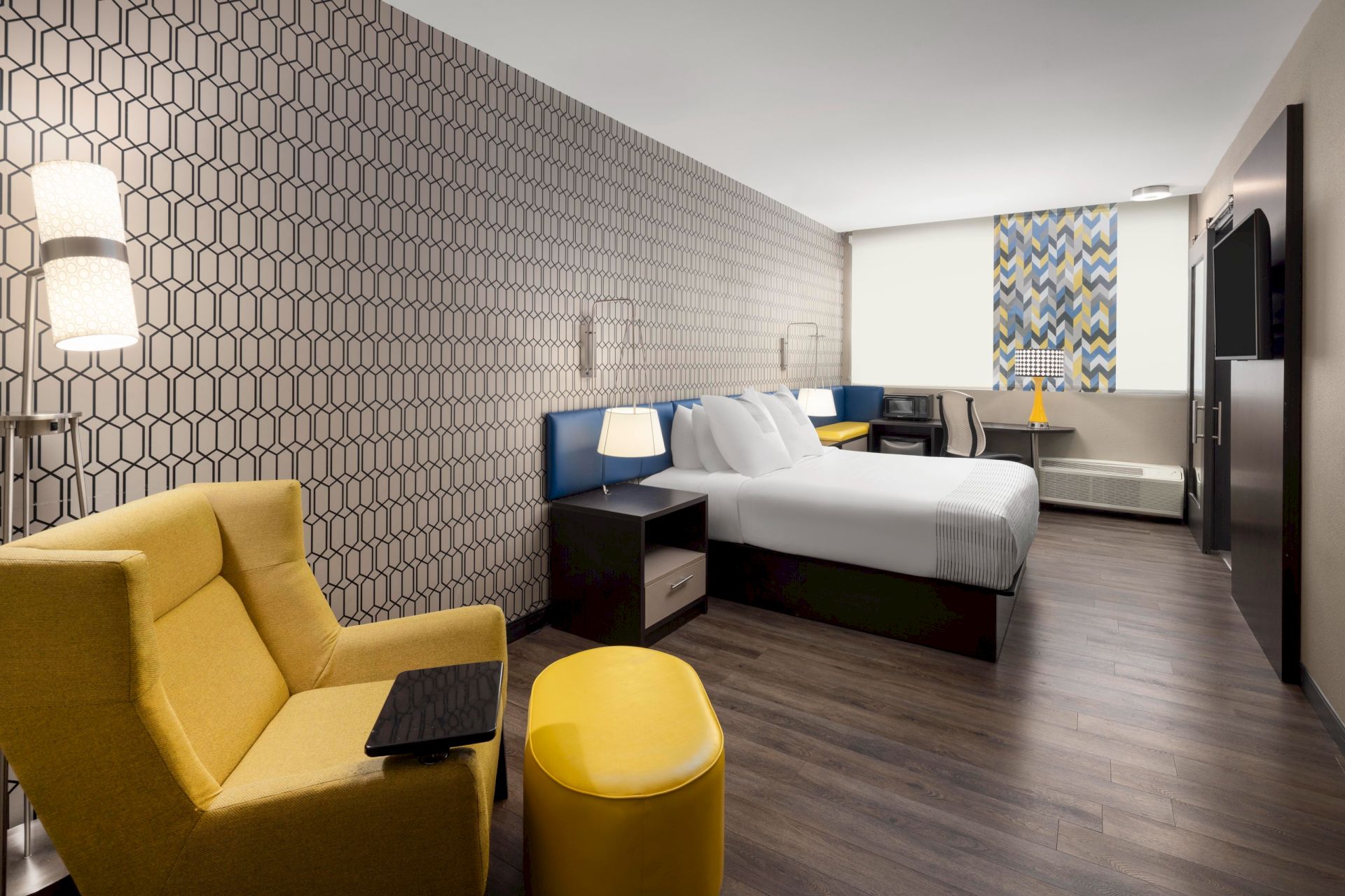 King guest room with a yellow lounge chair, work desk and television.
